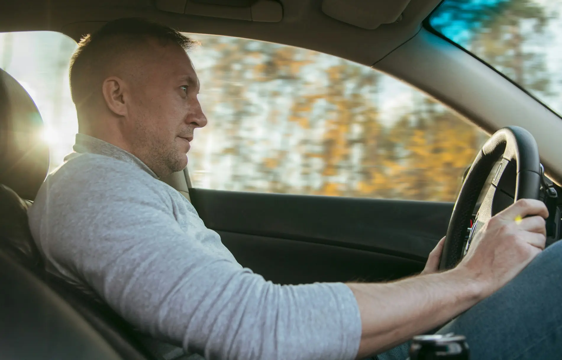 An adult driver at the wheel in afternoon light, relaxed and looking ahead